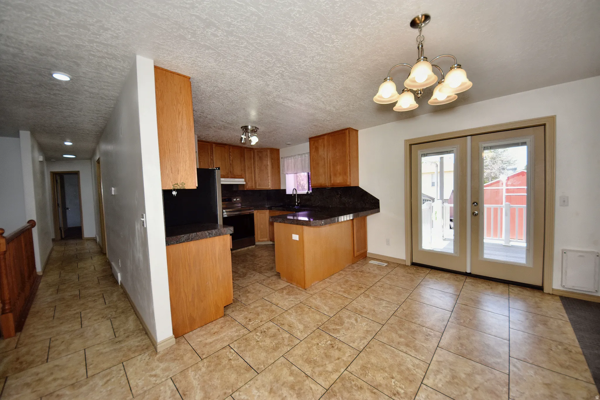 Kitchen and dining area featuring wood cabinetry, dark countertops, a central island, and tile flooring