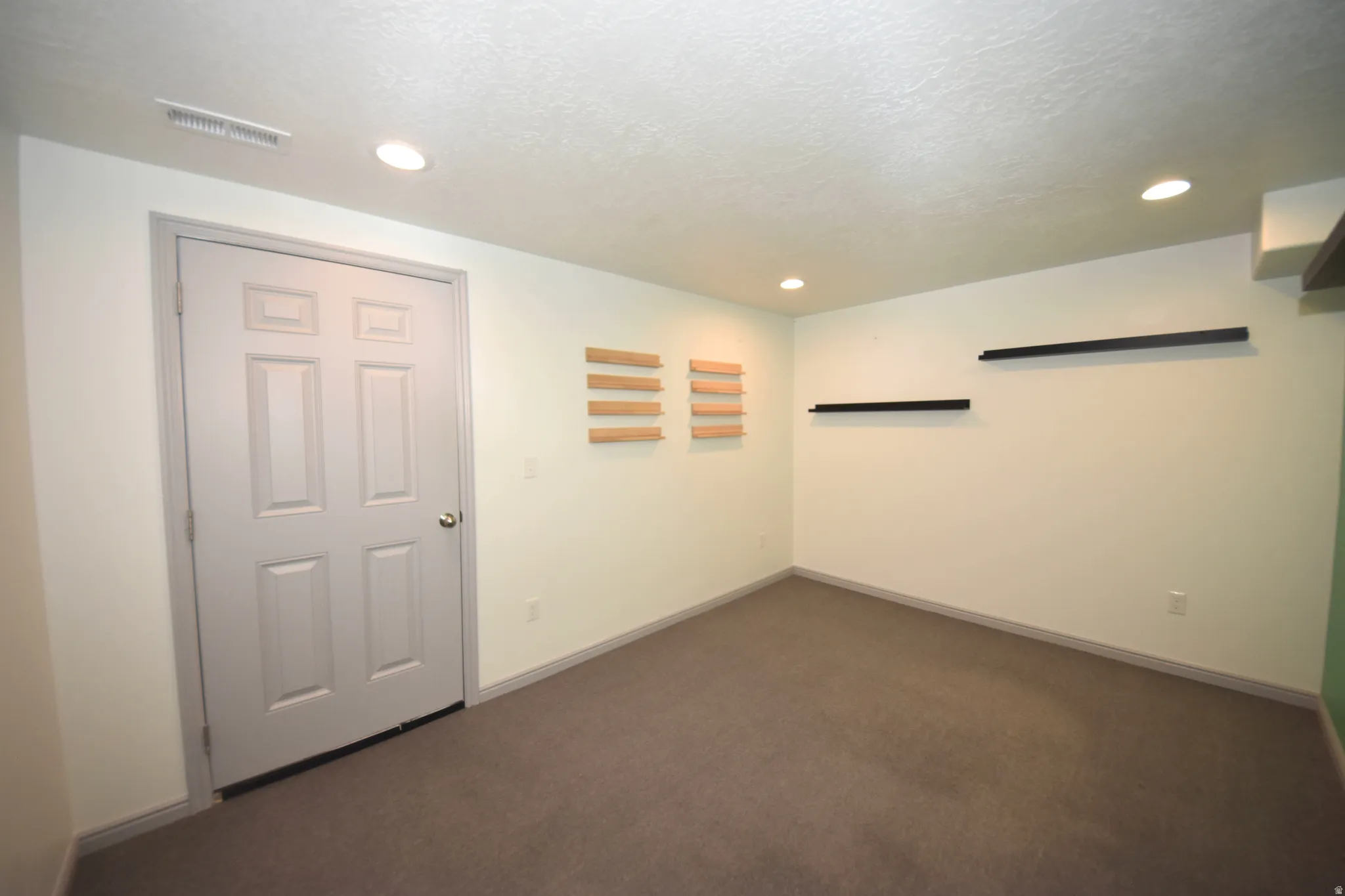 Interior room with recessed lighting, light-toned walls, and dark gray carpeting