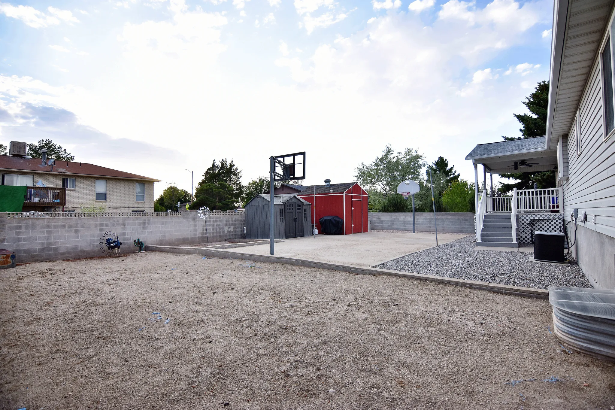 Expansive backyard featuring a concrete patio, gravel border, and a concrete block retaining wall