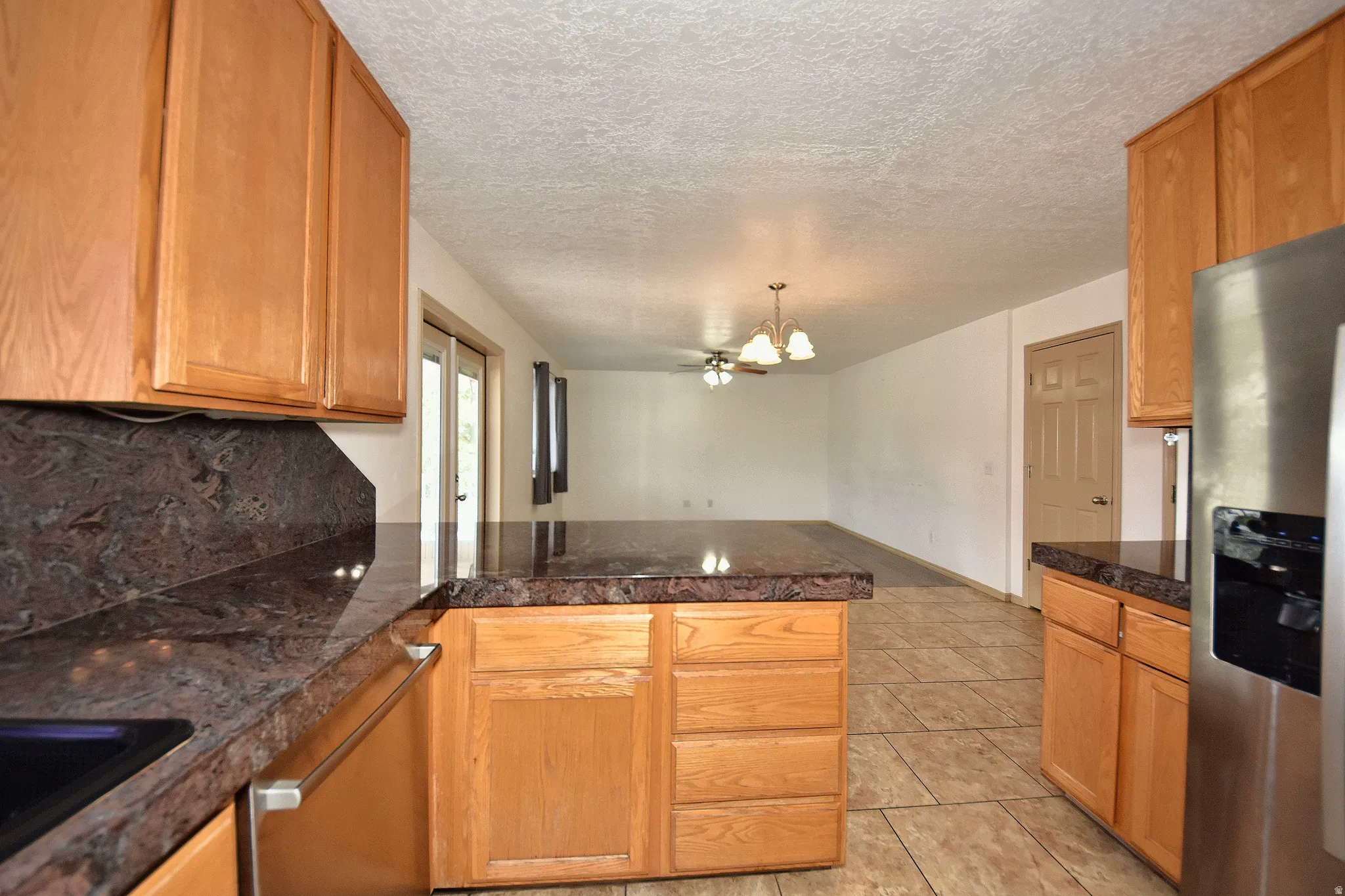 Kitchen featuring wood cabinetry, dark granite-look countertops, and tile flooring