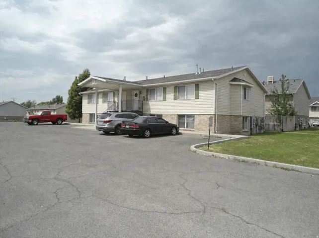 Multi-unit building featuring cream-colored siding and a stone-clad foundation