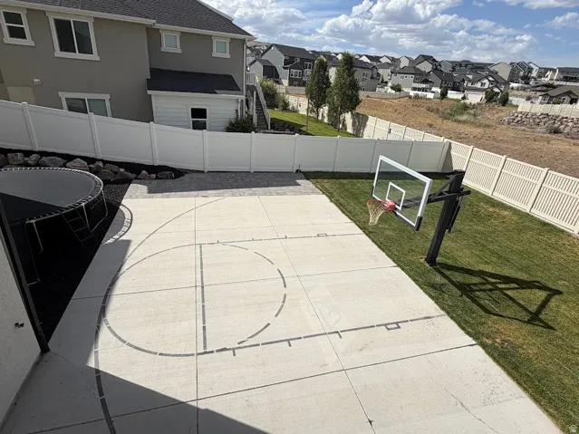 Expansive concrete pad featuring painted court lines and a dedicated basketball hoop
