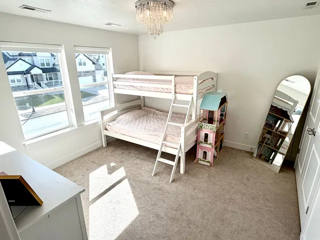 Well-appointed room featuring two large windows, neutral carpet flooring, a decorative ceiling light fixture, and white painted walls