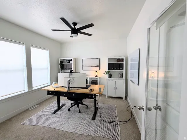 Beautiful office with dual windows, and a ceiling fan.