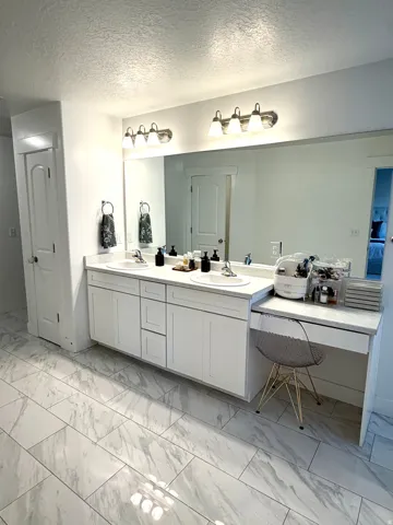 Dual vanity featuring white cabinetry, integrated sinks, and polished chrome fixtures
