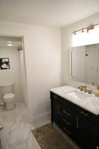 Vanity with a marble countertop, undermount sink, and brass-finish hardware