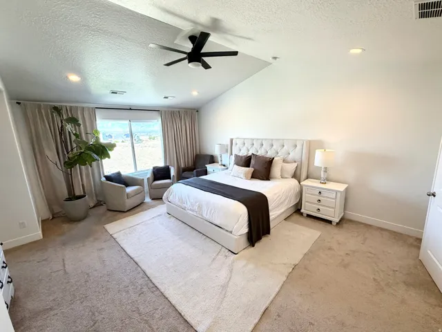 Vaulted ceiling with recessed lighting and a ceiling fan, broad window with full-length drapery, and neutral carpeting
