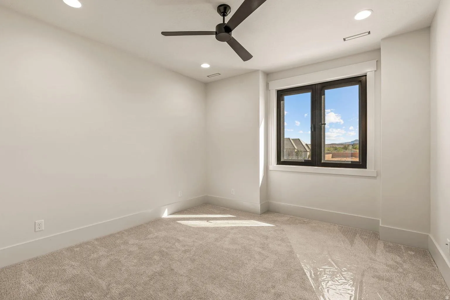 Bright room with a modern black ceiling fan, recessed lighting, and a large window featuring dark frames
