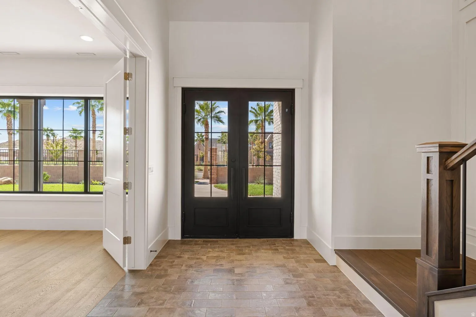 Entryway featuring a dark wood double door with glass lites, tile flooring, and white trim