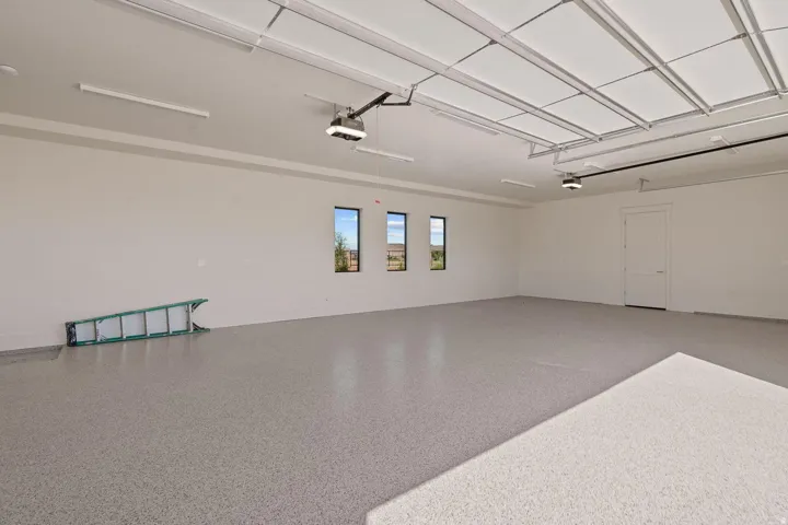 Spacious garage featuring a light-toned finished floor, multiple windows, and a side access door