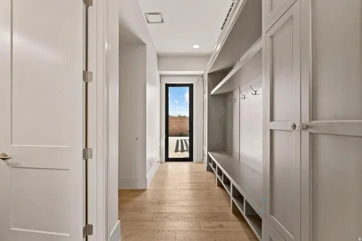 Hallway featuring wood-finish flooring, recessed lighting, and a built-in mudroom bench with storage cubbies and coat hooks