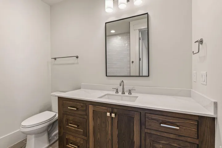 Bathroom featuring a dark wood-finish vanity with an integrated sink, a white countertop, and contemporary brushed nickel hardware