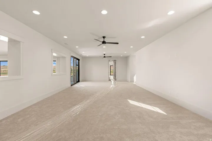 Spacious room featuring light-colored carpet flooring, recessed lighting, and dual ceiling fans