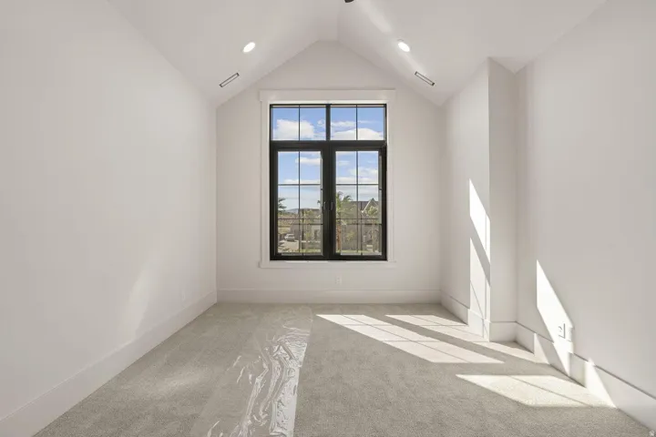 Vaulted ceiling with recessed lighting and a large black-framed window
