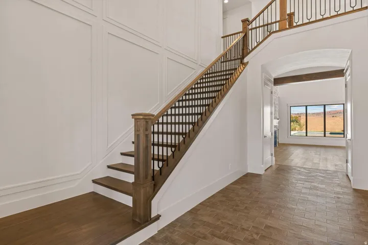 Grand staircase featuring wood treads, wood newel posts, and decorative metal balusters