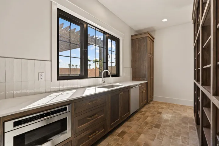 Kitchenette featuring a stainless steel under-counter microwave, a stainless steel dishwasher, and a single basin sink with a gooseneck faucet