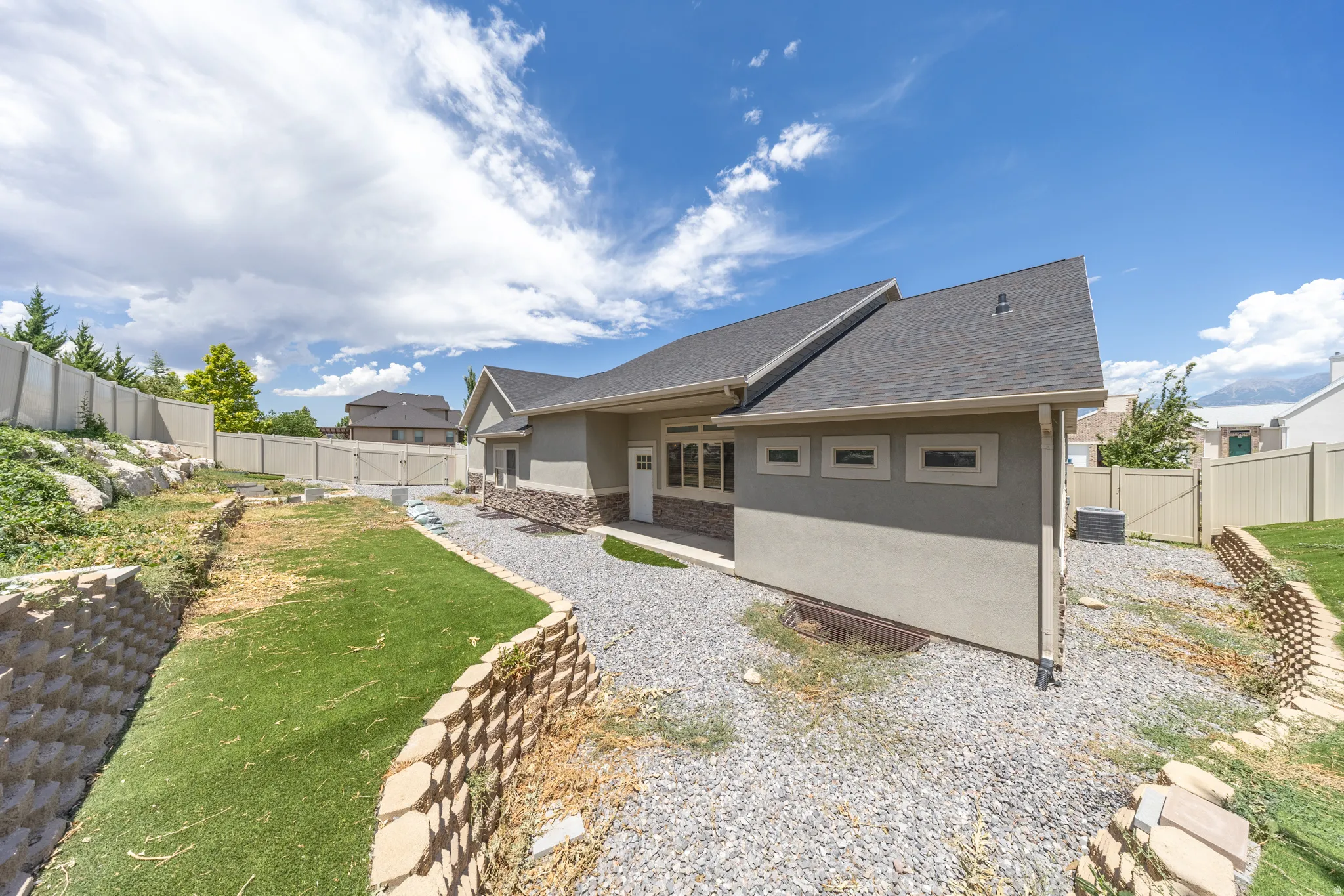 View of back yard from SW corner. Terraced yard with retaining wall. Covered patio.