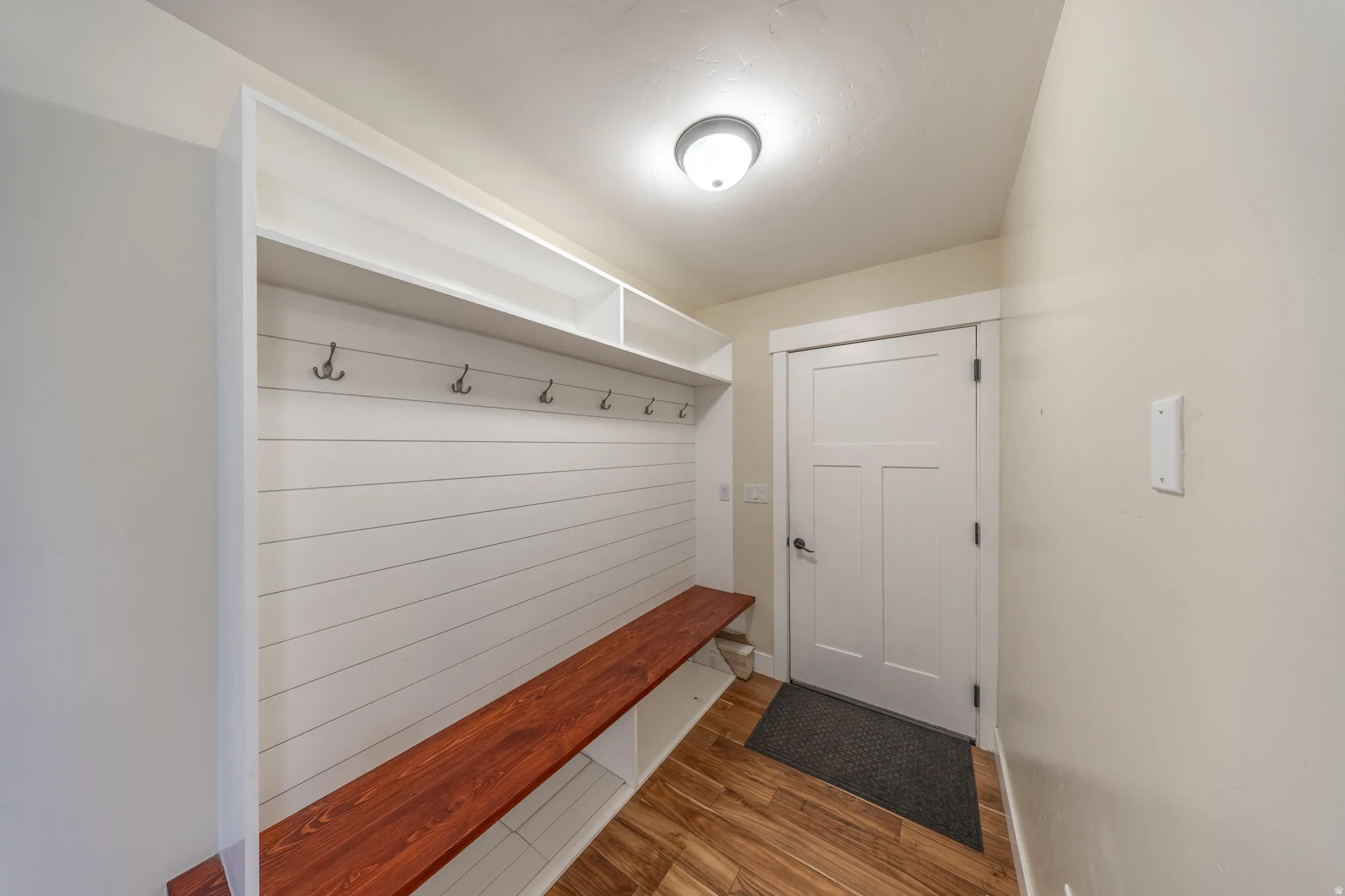 Built-in mudroom bench with natural wood finish, shiplap backing, and integrated storage shelving. (entry from garage)