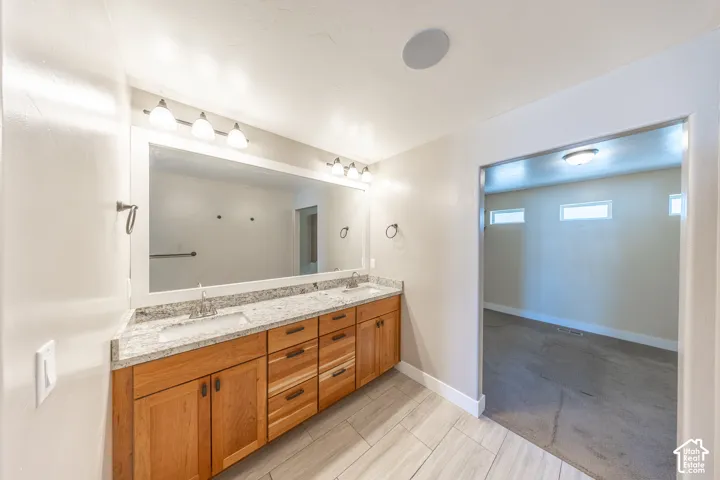 Primary suite bath features a dual vanity with wood cabinetry, granite countertop, and undermount sinks