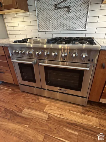 Stainless steel professional-grade range with double ovens, a six-burner gas cooktop, 15,000 BTU flat top skillet and a pot filler faucet mounted on backsplash.