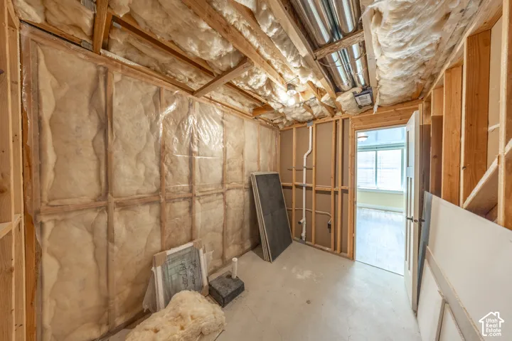 Framed interior space featuring exposed insulation, wood ceiling beams, and concrete flooring