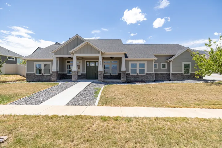 Ranch-style residence featuring a prominent covered entryway with white columns and a dark green door