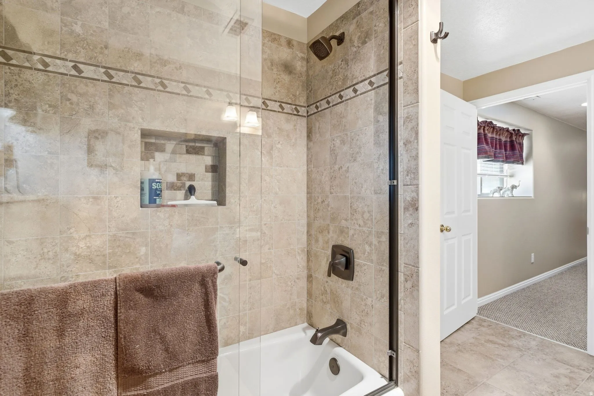 lower level bathroom suiteTiled shower with glass enclosure, built-in niche, and oil-rubbed bronze fixtures