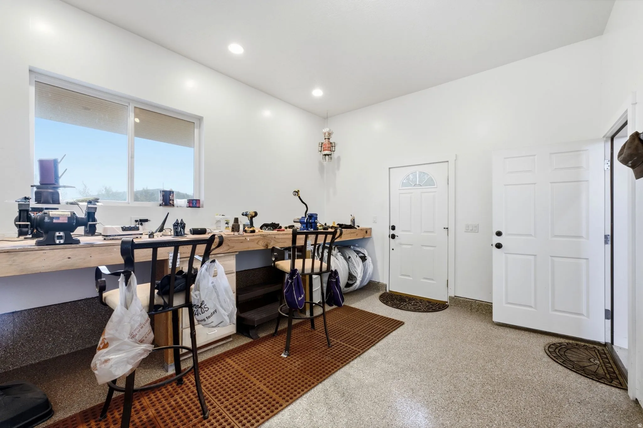 Spacious utility area featuring a large window, recessed lighting, two panel doors, and epoxy flooring