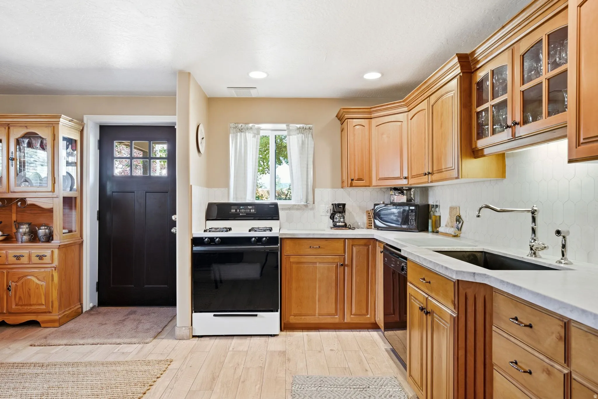 lower level kitchen with Light wood-finish flooring complements the natural wood cabinetry and light countertops