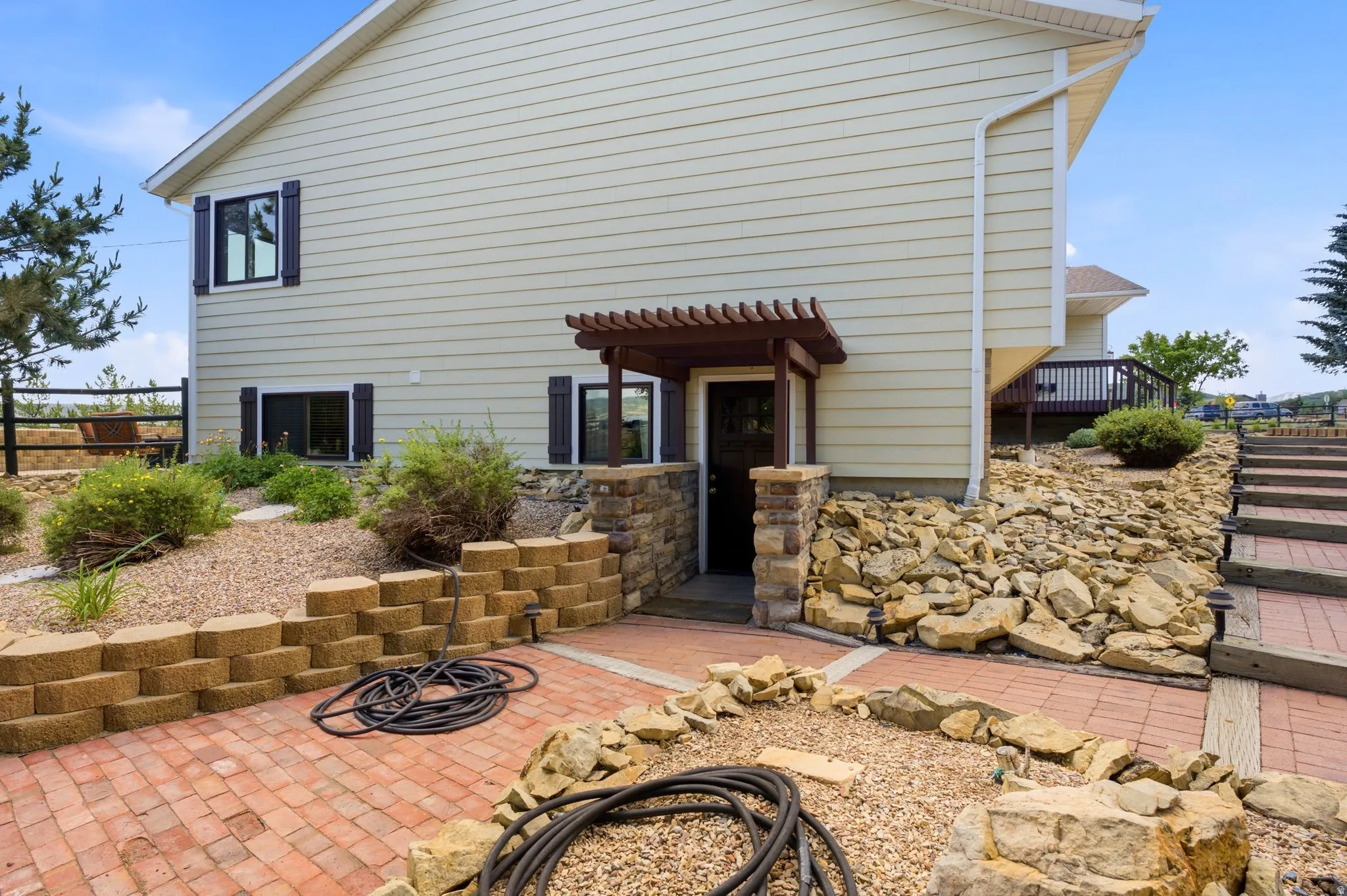 Exterior lower level entrance featuring a wood pergola and stone column accents