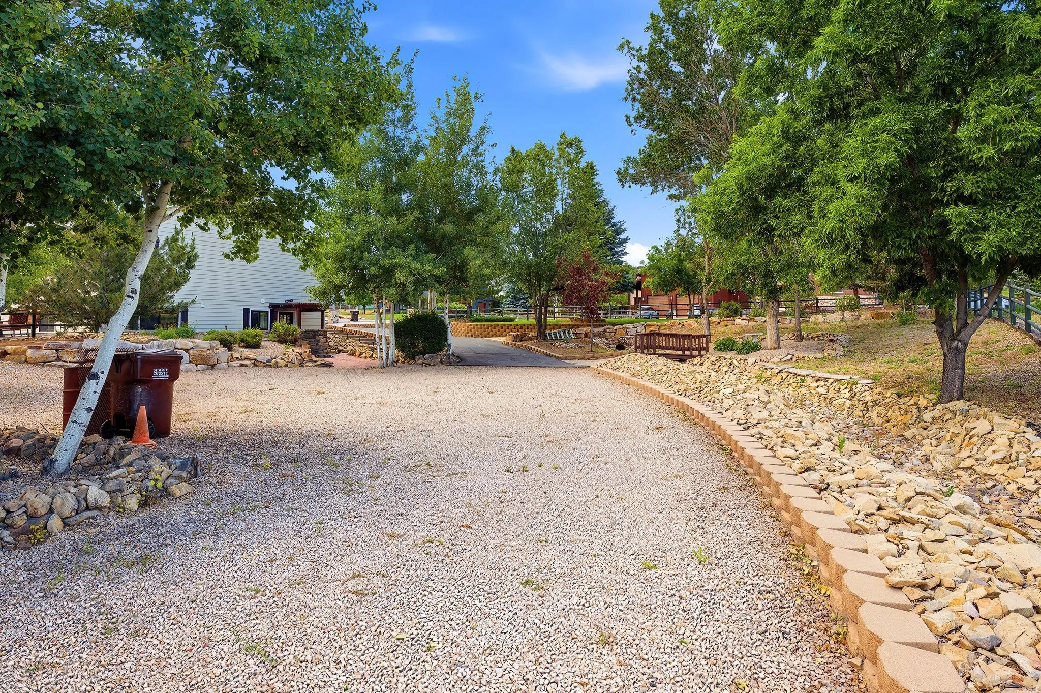Gravel path bordered by a stone retaining wall and mature trees