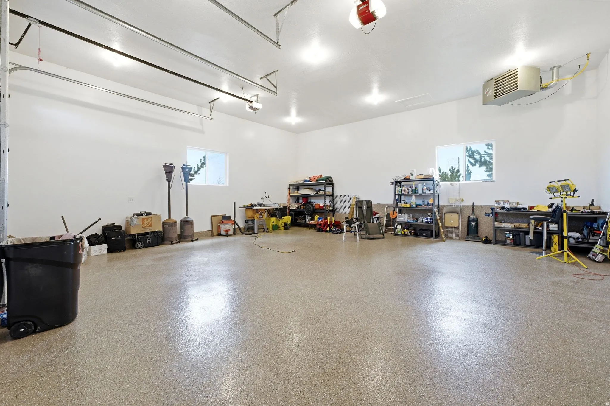 Expansive garage featuring a speckled epoxy floor, multiple windows for natural light, and overhead lighting fixtures