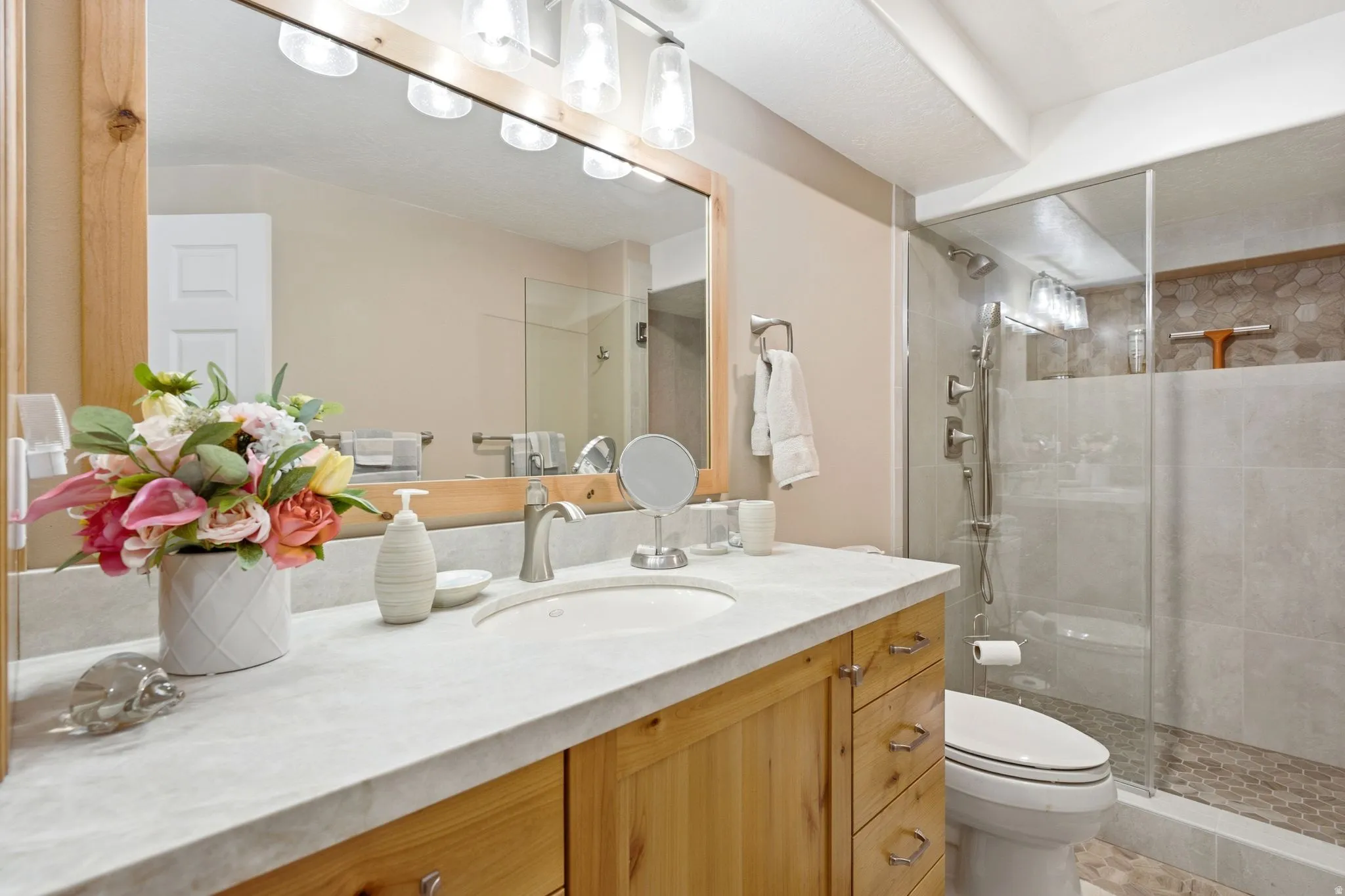 Bathroom featuring a single vanity with wood cabinetry, a light-toned countertop, and an undermount sink