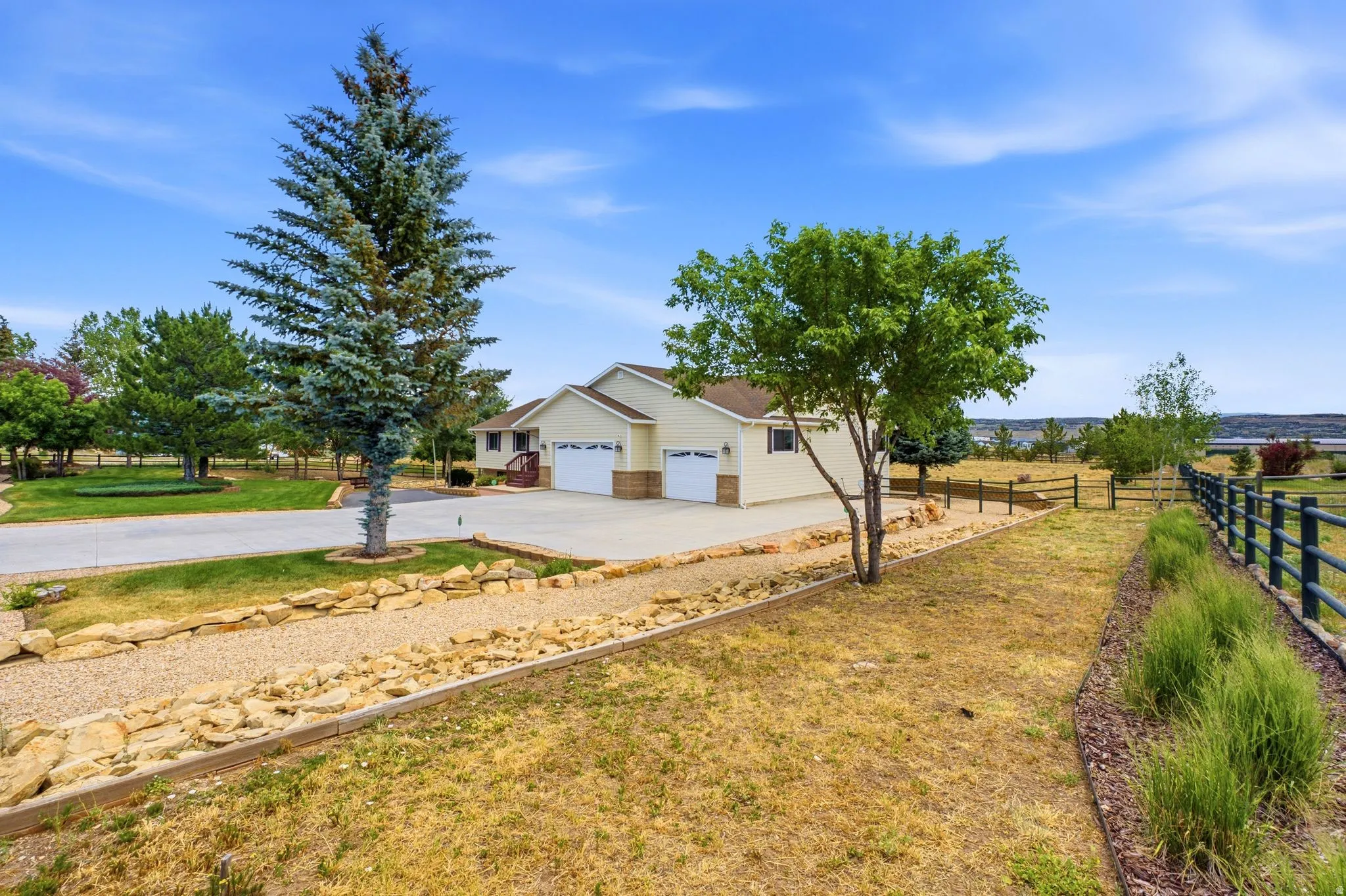Spacious property featuring a light-colored exterior, an expansive driveway, and a multi-car garage
