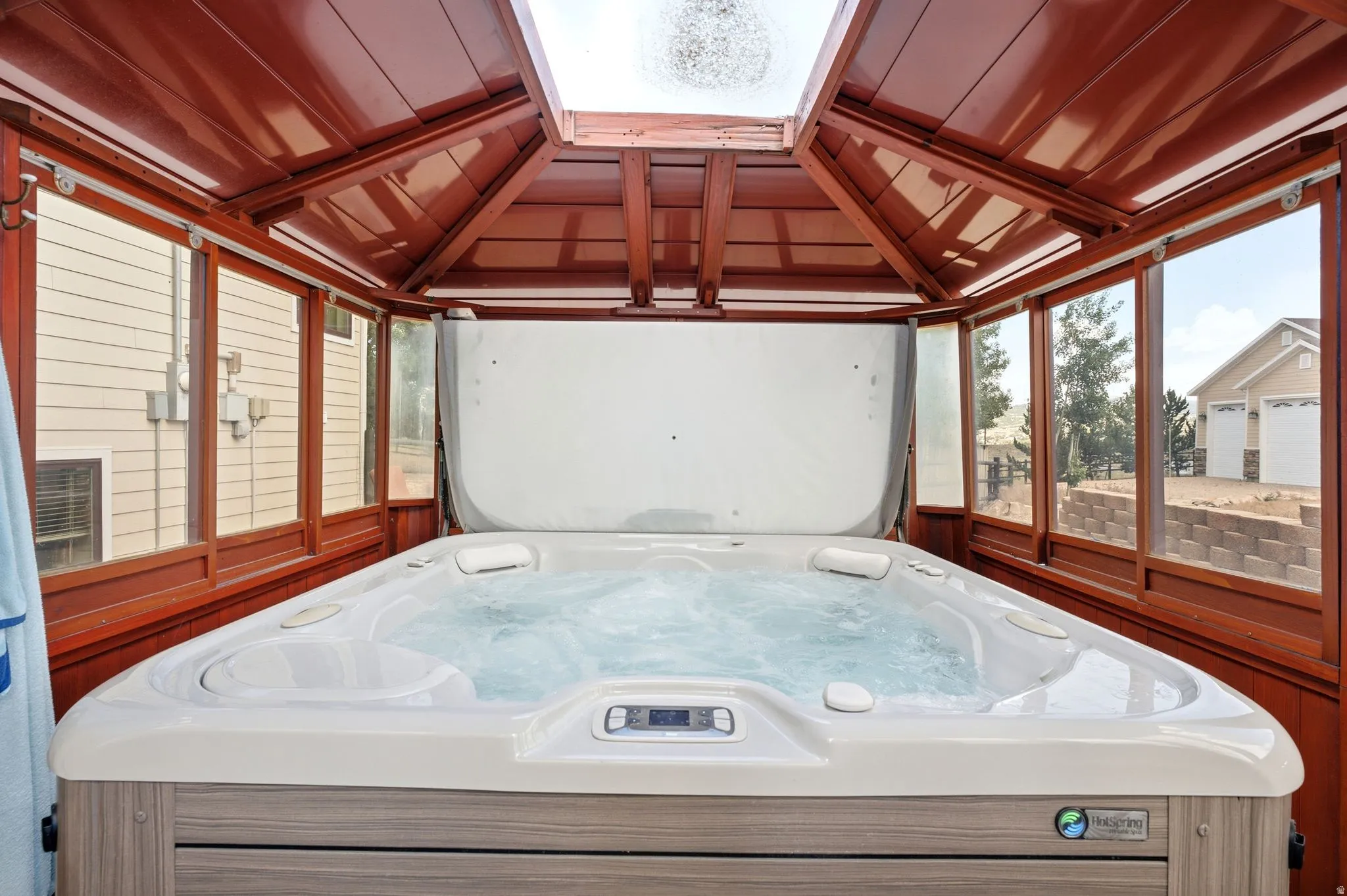 Enclosed hot tub within a gazebo featuring a wood-finish interior and a clear skylight