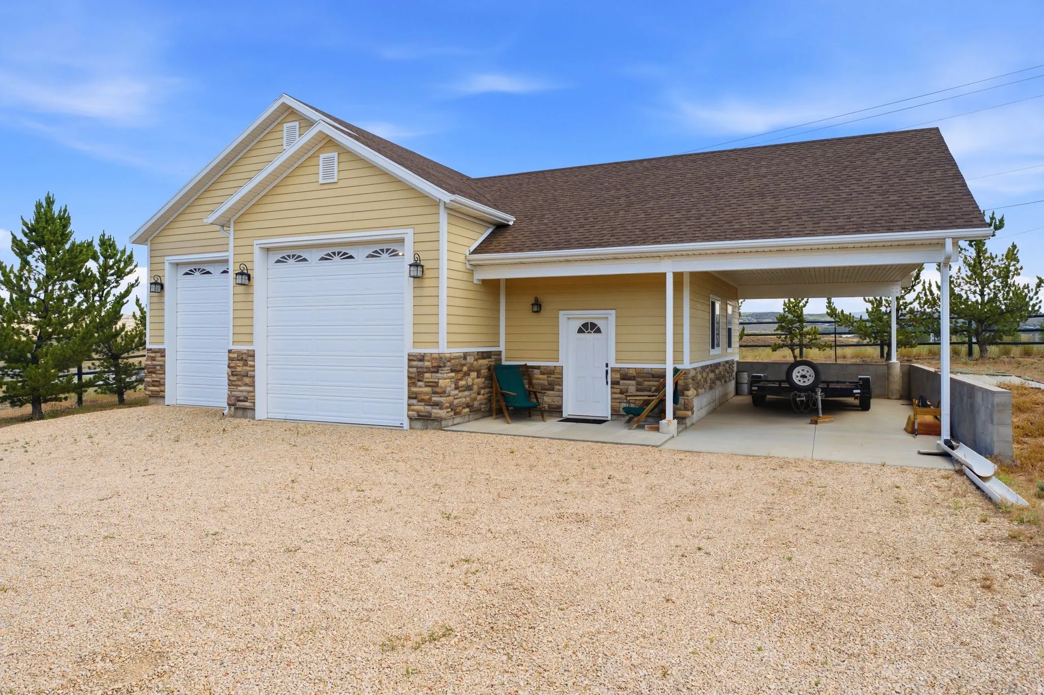 Detached garage structure featuring two overhead doors with decorative glass inserts, an attached carport, and a separate entry door