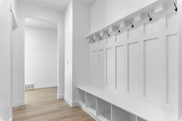 Built-in board and batten mudroom unit featuring a bench with integrated cubbies and black coat hooks