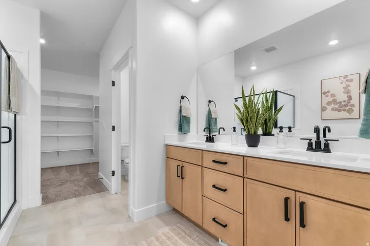 Double vanity with light wood-finish cabinetry, white countertops, and matte black fixtures