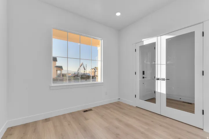 Room featuring light wood-finish flooring, white baseboards, and bright white walls