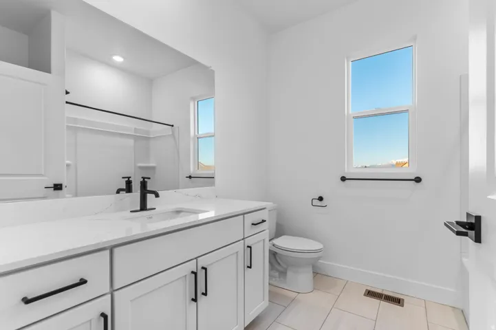 Bathroom featuring a vanity with a white countertop and undermount sink, matte black faucet, and white shaker-style cabinetry with matte black hardware