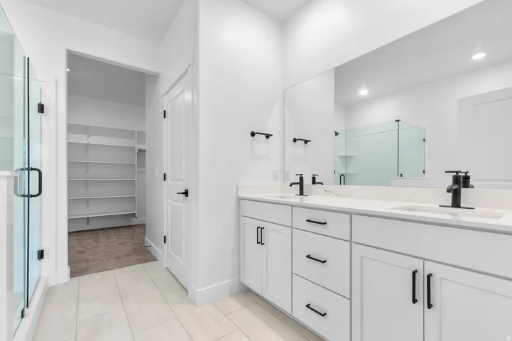 Double vanity with quartz countertops, matte black fixtures, and integrated sinks
