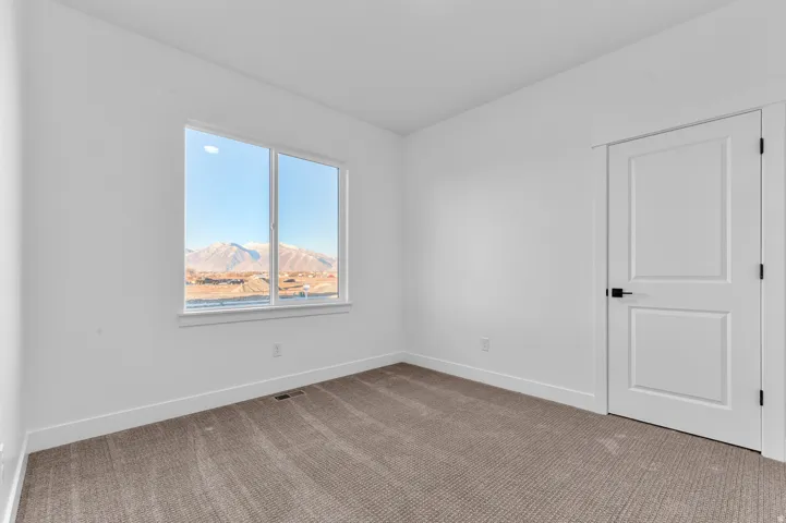 Room featuring a large window, mountain backdrop, white walls, dark gray carpet, and a white two-panel door with black hardware