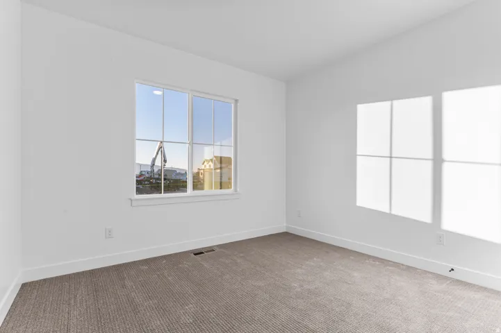 White interior room featuring a large multi-pane window, neutral carpet flooring, and white baseboards