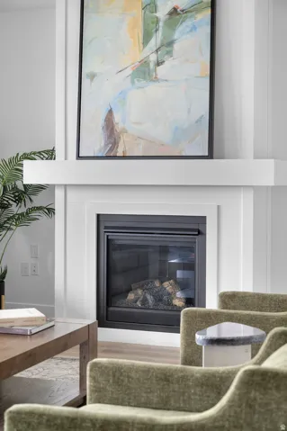 Built-in fireplace featuring a black glass-front insert and log media, framed by a shiplap-style surround and a substantial white mantel