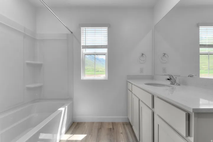 Bathroom featuring a single vanity with light-colored cabinetry and a solid surface countertop