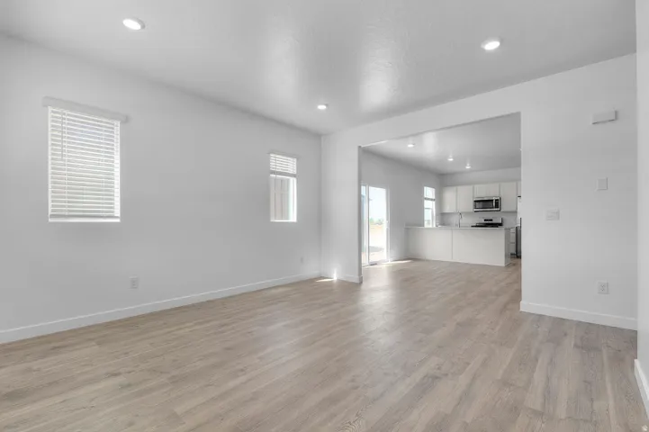 Expansive living area featuring light wood-finish flooring, recessed lighting, and a neutral white color palette