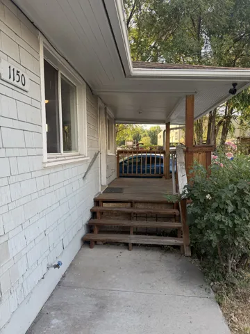 Covered porch entry featuring a multi-level wood deck and concrete pathway