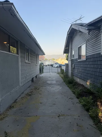 Concrete walkway between two structures with horizontal siding and shingle accents