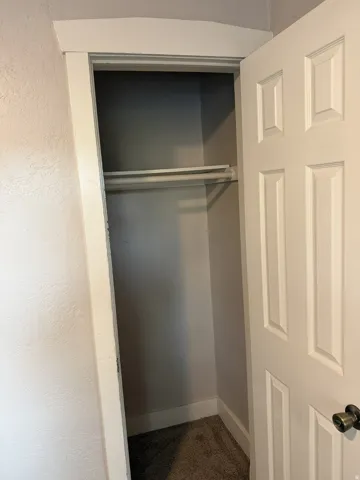 Recessed closet with two clothing rods, paneled door, and textured walls