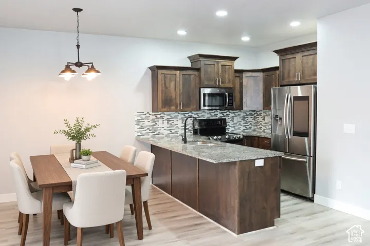 Kitchen featuring wood-finish cabinetry, stainless steel appliances, granite countertops, and a patterned tile backsplash